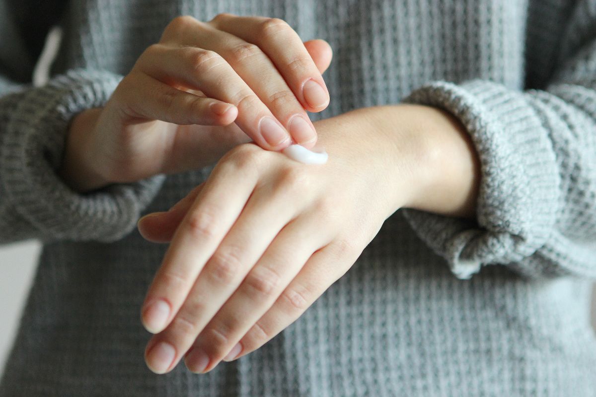 Pige smører creme på hænder